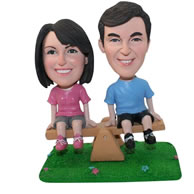 Custom couple sitting on a teetertotter figurines