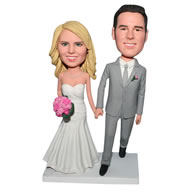 Groom in grey suit and bride in white wedding dress handing with a bunch of flowers bobblehead