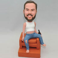 Personalized bobbleheads sit in the chair with a bottle of beer