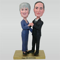 Huaband in black suit and wife in blue dress with their 50th anniversary custom bobbleheads