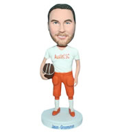 Man in white T-shirt matching with orange pants handing football bobblehead