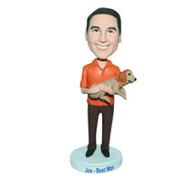 Man in orange T-shirt carrying his pet dog bobblehead