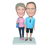 Glasses husband in blue shirt and wife in pink shirt carrying a bag bobblehead