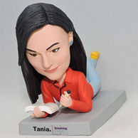 Custom girl bobblehead lieing on the base with a book